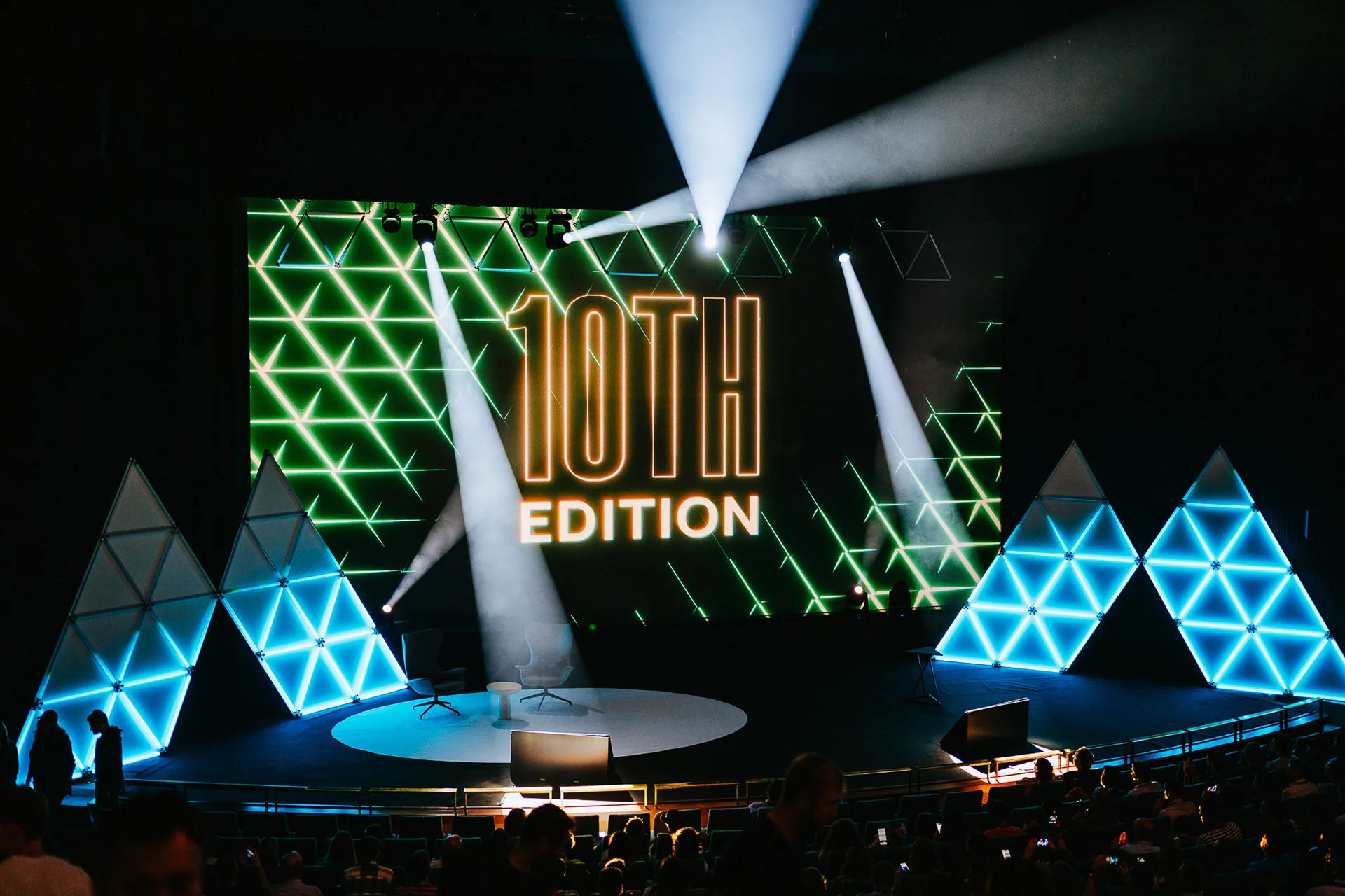 Marketing Festival main stage with a 10th Edition screen, light beams and glowing triangle panels