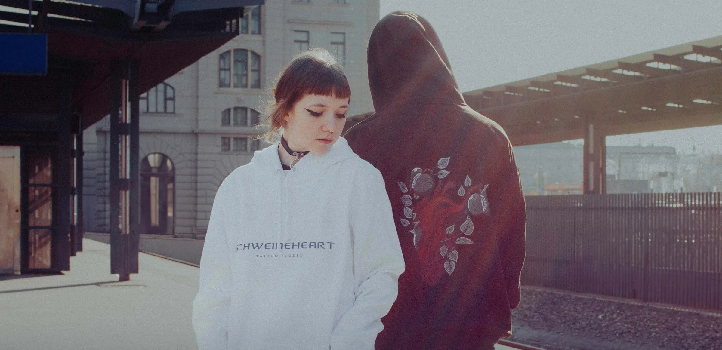 Two people in Schweineheart hoodies at a train station